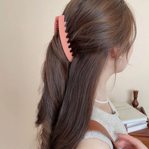 Gros plan d'une pince à cheveux mate orange corail tenant une coiffure élégante relevée