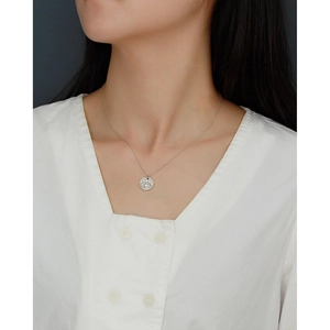 Close-up of a silver s925 evil eye necklace with crystals worn on a white shirt