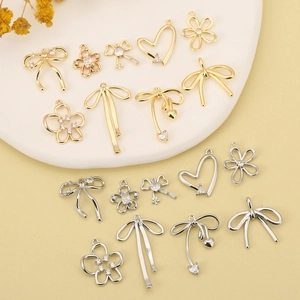 Assorted 18K gold and silver bow, heart, and flower charms with zircon inlay on tray