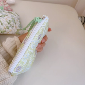 Mini floral cotton coin purse with purple flowers and green zipper pull held in hand