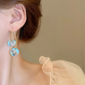 Close-up of light blue glass cherry earrings on model with golden hooks and sheer fabric