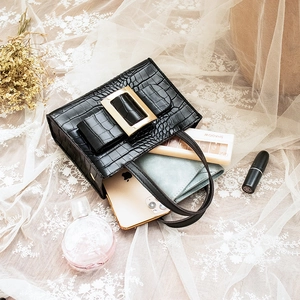 Elegant black crocodile texture handbag with gold buckle shown with personal essentials