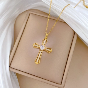 Close-up of gold hollow cross necklace with square zircon in a beige jewelry box