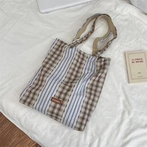 Detail of vintage plaid patchwork tote bag with brand logo on a soft lifestyle background