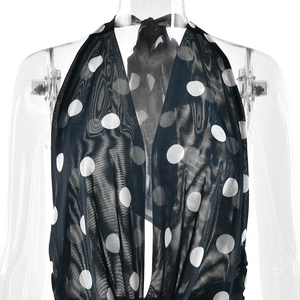 Détail du tissu en maille à pois noirs avec col en V profond et licou sur fond blanc