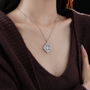 Gros plan d'un collier trèfle argenté avec une pierre centrale et des cristaux brillants