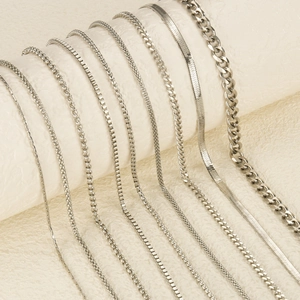 Detailed close-up of multiple stainless steel chain styles including snake and curb links