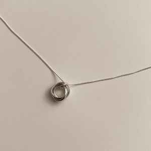 Macro detail of silver tiered triple circle pendant on a delicate minimalist chain