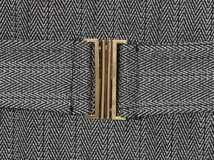 Détail de la ceinture en tissu à chevrons avec une boucle en métal doré poli brillant