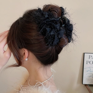 Gros plan sur une pince à cheveux noire duveteuse avec paillettes argentées sur chignon
