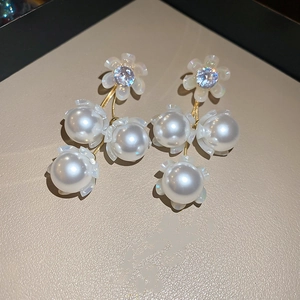 Détail de boucles d'oreilles muguet avec base fleurie dorée et perles pendantes
