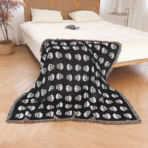 Bohemian knit throw blanket with skull pattern and colorful tassels on white bed