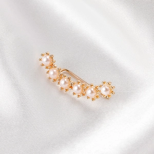Macro view of a gold-plated ear cuff featuring six elegant pearls on white silk