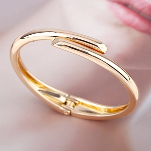 Minimalist gold-plated polished stainless steel bangle with a unique overlap design