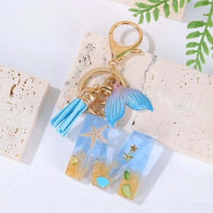Detailed macro view of resin letter M keychain featuring blue beach and mermaid tail