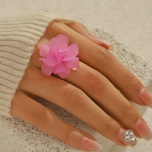 Close-up of a pink woven resin flower ring worn by a model with soft lighting