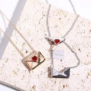 Detail of gold and silver envelope necklaces with heart gems and I love you engraving