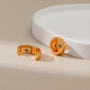 Minimalist 18K gold plated hoop earrings displayed on a white ceramic plate