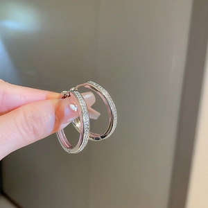 Macro shot of silver paved cubic zirconia hoop earrings held to show texture