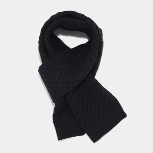 Detail view of the thick black knitted scarf showing premium wool texture and pattern