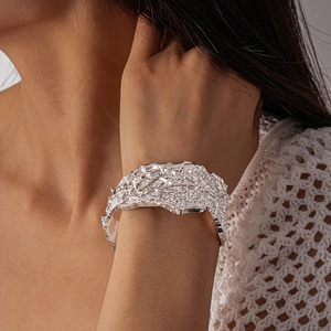 Macro detail of silver wide cuff bracelet with irregular crushed lava texture and glossy finish