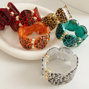 Detail of resin leopard print bracelets with gold spacers on white ceramic background