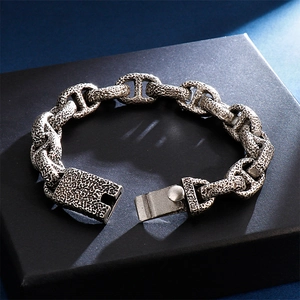 Vintage oxidized stainless steel link bracelet with textured finish on a display box