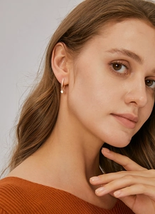 Detail of gold-plated U-shaped drop earring with micro-set zircon on model