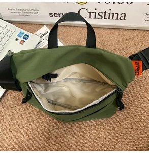 Close-up of green nylon crossbody bag showing inner pocket and orange brand label