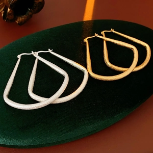 Détail de boucles d'oreilles créoles texturées en métal doré et argenté style éventail