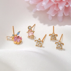 Macro shot of a five-piece floral and star earring set with pink zircons on white silk