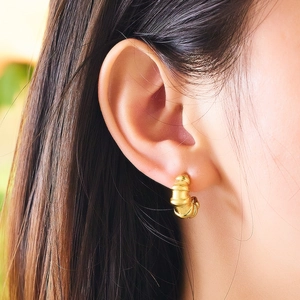 Close-up of golden twist hoop earring featuring a chunky textured spiral design