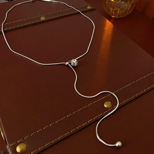 Detail of silver snake chain Y-necklace with geometric clasp and polished ball pendant