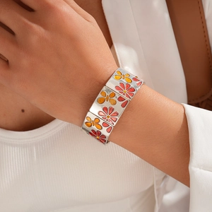 Détail du bracelet large en métal avec incrustation d'émail fleur et papillon