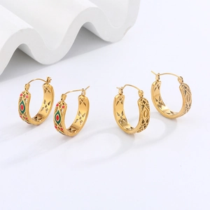 Detail of gold hoop earrings with red and green enamel and hollow geometric patterns
