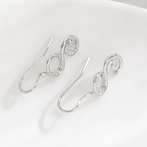 Macro detail of silver spiral geometric drop earrings with polished metallic finish