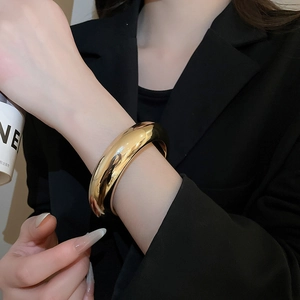 Gros plan d'un bracelet jonc doré épais avec finition miroir brillante sur un mannequin
