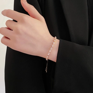Detailed view of a gold leaf-shaped zircon bracelet on wrist with adjustable chain detail