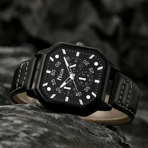 Macro shot of a black octagonal quartz watch on a textured rock showing leather strap details