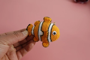 Dettaglio del portachiavi a forma di pesce pagliaccio fatto a mano su sfondo rosa tenue