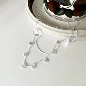 Detail showing the layered silver snake chain with polished round sequin pendants