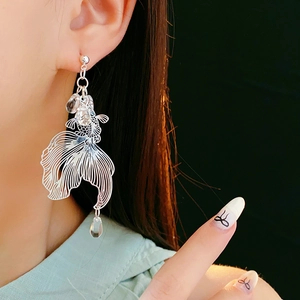 Detail of silver koi fish earring with transparent crystal drop worn on model