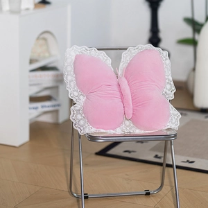 Detailed view of a pink butterfly pillow with white lace trim on a transparent chair
