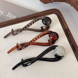 Detail of glossy resin hair claws in brown, dark grey and black on a rustic wooden tray