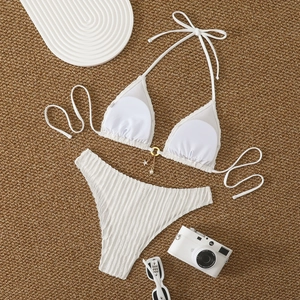 Detail of white textured bikini fabric with gold ring and pearl star pendants