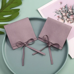 Close-up of lilac microfiber velvet jewelry pouches with ribbons on a green display plate