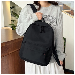 Detailed view of black lightweight nylon backpack with zipped front pocket on model