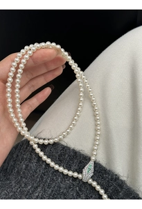 Close-up of pearl necklace featuring a snake-shaped clasp with green zircon and micro-inlays