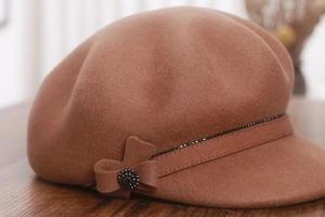 Detail of wool octagonal cap with brown texture and beaded bow decoration