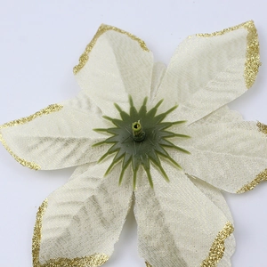 Detailed close-up of cream artificial Christmas flower with gold glitter edges and fabric texture